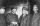 Photo en noir et blanc de quatre hommes en tenue de porteurs ferroviaires. Tous les quatre sourient et les deux du centre se serrent la main.